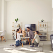 Family room trends for 2022 - Happy family father mother and two children sitting on floor and playing at home together during weekend. Family spending happy time at home and having fun with children concept